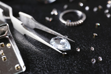 Jewels and tweezers on black leather surface