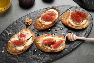 Bruschettas with ripe figs and cream cheese served on grey table, top view