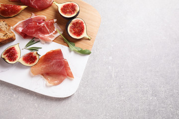 Delicious ripe figs, prosciutto and toasted bread served on table, top view. Space for text