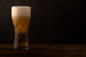 Glass beer on dark wood background with copyspace