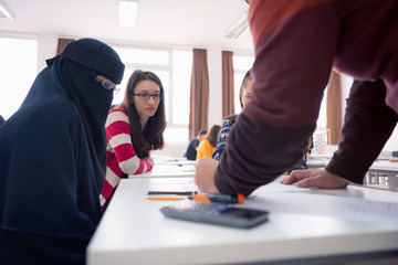 Male professor of architecture explain lesson to multiethnic students and interact with them in the modern classroom.Helping a students during class.