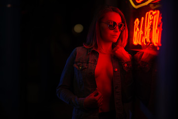 Sexy portrait of a young girl with an open bust in sunglasses and with in the night city, in the...