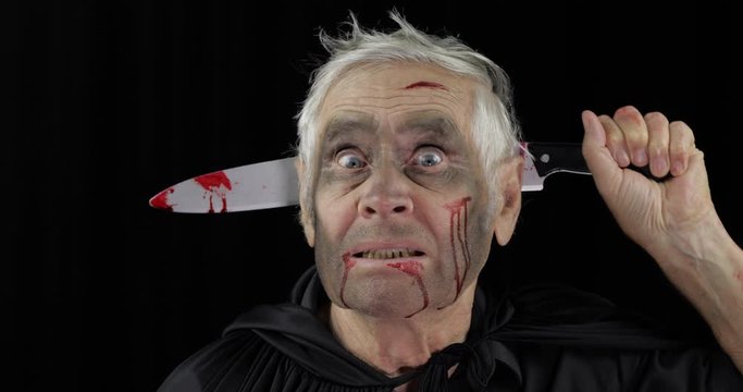 Elderly man with knife in head. Halloween makeup and costume. Blood on his face