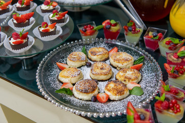 Cheesecakes with sour cream, mint, strawberries on a breakfast buffet