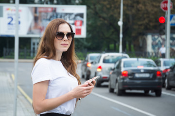 Fototapeta premium Cheerful attractive young woman with red backpack and book walking in the city