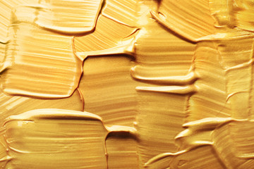 Strokes of gold paint as background, top view