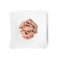 Plate with canned tuna on white background, top view