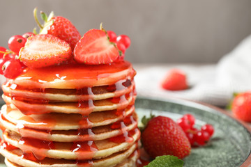 Delicious pancakes with fresh berries and syrup on table, closeup