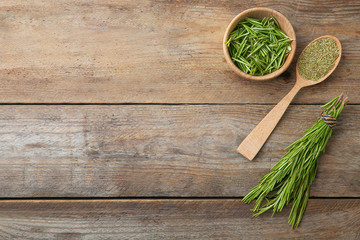 Dried rosemary and fresh twigs on wooden background, flat lay. Space for text