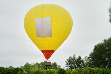 Obraz premium Yellow Hot air balloon over the green forest trees