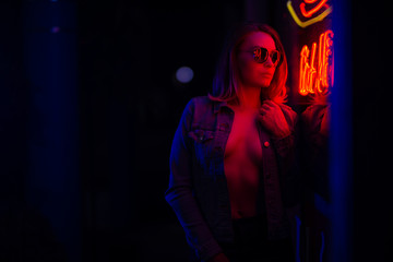 Sexy portrait of a young girl in sunglasses and with in the night city, with creative light on the...