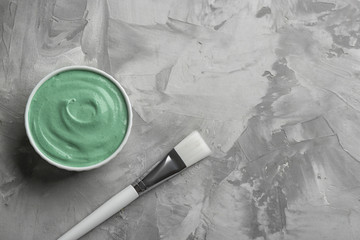 Spirulina facial mask and brush on grey table, flat lay. Space for text