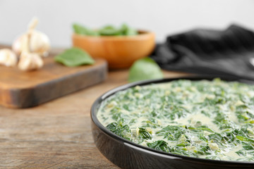 Tasty spinach dip on wooden table, closeup