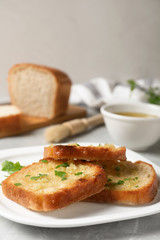 Slices of toasted bread with garlic and herb on light grey marble table