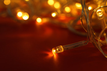 Glowing Christmas lights on red background, closeup