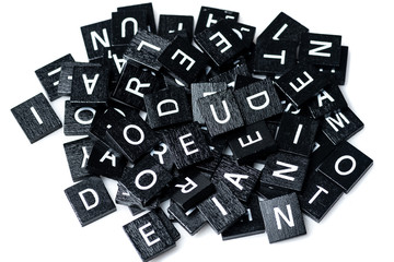 Heap of Black Wooden Scrabble letters on white background