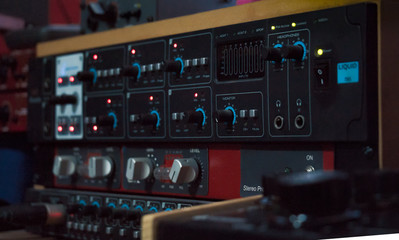 Consola de sonido en primer plano, puesta en perspectiva. Perillas, botones y luces led sobre el panel negro. 