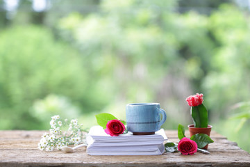 Vintage blue cup with red roses and diary notebook and small cactus  on wooden table