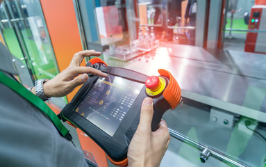 worker holding smart panel to control automatic robot in ai factory