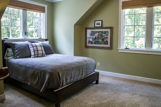 A Bedroom With Green Walls And Gray Bedding And A Plaid Pillow With A Window Behind The Bed