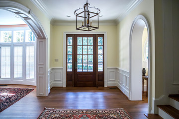 front entrance foyer hallway of a large home house with yellow walls and a wood door with windows...
