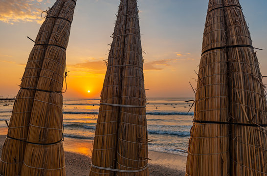 Traditional totora reed boats on Huanchaco Beach at sunset near the city of Trujillo, Peru.