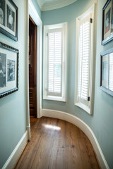 Fototapeta na wymiar curved green hallway with windows and hardwood floors