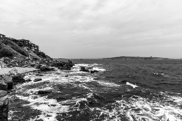 Obraz premium The rocky coast of the Black Sea near the ancient city of Sozopol. Bulgaria. In the In the background are the islands of St. Peter and St. Ivan. Black and white.