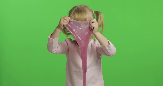 Kid playing with hand made toy slime. Child having fun making pink slime