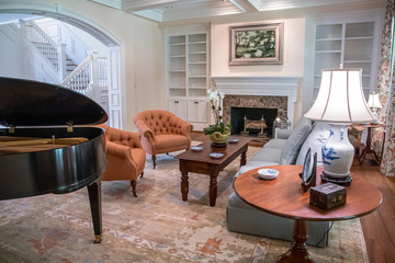 large formal living room in a spacious home. Arched doorway entrance and comfortable furniture with a baby grand piano. Coffered ceiling and a lot of natural light from the large windows.