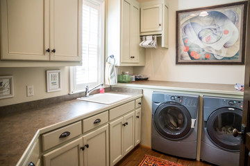 Large cream white laundry room with a window and natural light