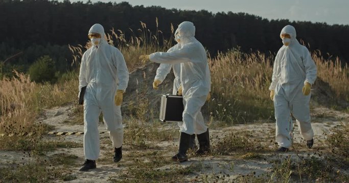 Team of ecology experts working in polluted open area countryside toxic contamination. Environmental operation.
