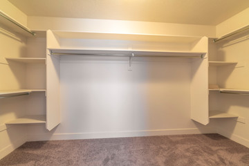 Empty walk in closet of a new home with shelves and metal rods for clothes