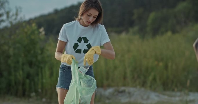 Attractive and helpful young people cleaning down the lake beach together supporting ecology movement future generation. Nature preservation concept.