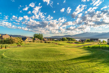 Fototapeta na wymiar View of a golf course on a sunny day with homes lake and mountain background