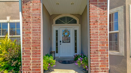 Panorama Flowers and white door with sidelights and transom window at the entrance a home