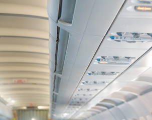 Blurred photo of the aircraft interior. The ceiling of the airplane with luggage compartment