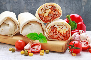 A burrito - mexican dish that consists of a flour tortilla with various ingredients.