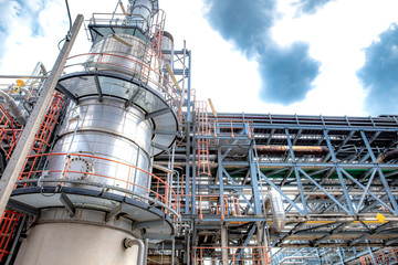 Oil and gas industrial refinery zone,Detail of equipment oil pipeline steel with valve from large oil storage tank at cloudy sky. -image