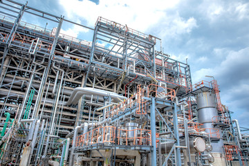 Fototapeta premium Oil and gas industrial refinery zone,Detail of equipment oil pipeline steel with valve from large oil storage tank at cloudy sky. -image