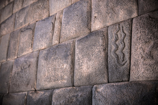 Inca wall with carved stone of snake at mythical street called seven snakes from Cusco, Peru.