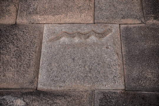 Inca wall with carved stone of snake at mythical street called seven snakes from Cusco, Peru.