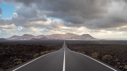 Larga carretera recta con linea continua al medio en el Parque Natural de los volcanes Timanfaya