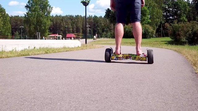 A man drives his hover board away along the pathway. A low angle steady shot