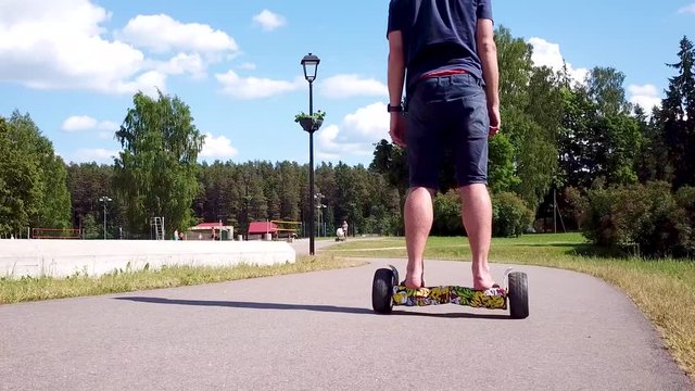 Man driving his hover board along the pathway almost falls. A long low angle zoom shot.
