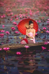 Fotobehang Lotusbloem Asia women on the boat in the lotus pond. She wears Thai traditional dresses.  © Ninja SS