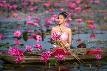 Fototapeten Asia women on the boat in the lotus pond. She wears Thai traditional dresses. © Ninja SS
