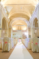 interno di chiesa addobbata con fiori e sedie bianche