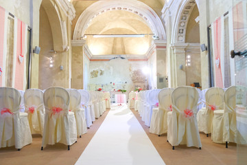 interno di chiesa addobbata con fiori e sedie bianche