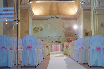 interno di chiesa addobbata con fiori e sedie bianche